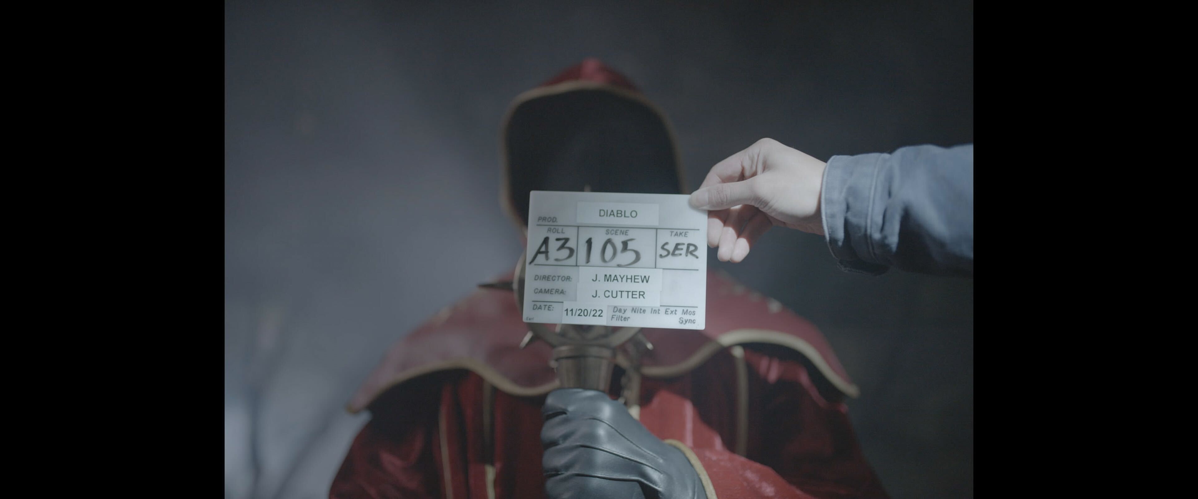 Diablo slate naming director J. Mayhew and camera J. Cutter in front of a hooded performer